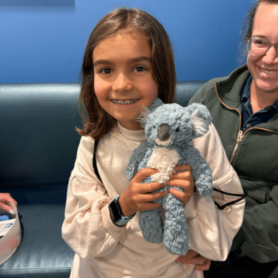 Little girl holding a blue stuffed koala at wake orthodontics & pediatric dentistry, representing solea vs traditional dentistry